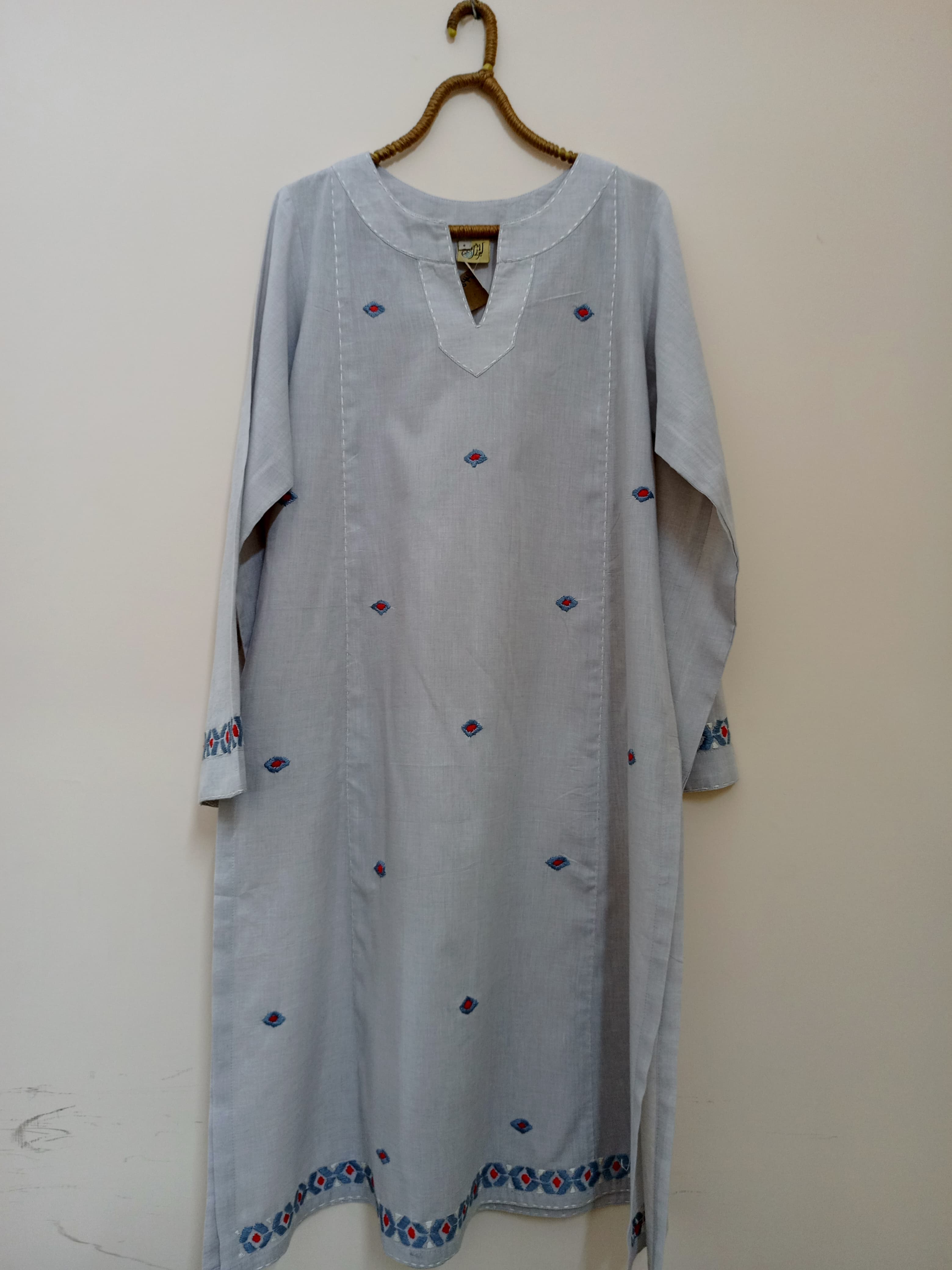 A soft grey shirt adorned with delicate floral hand embroidery, perfect for subtle everyday grace. Light yet elegant, it's your go-to choice for effortless seasonal transitions.